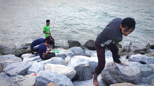 Man sitting on rock by sea