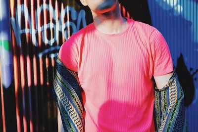 Midsection of man standing against multi colored store