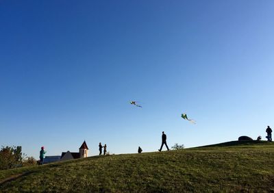 People on field against clear blue sky