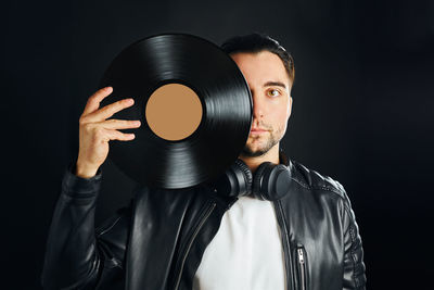 Music vinyl record. man holding black vinyl record over face. vintage music style. rock style. black