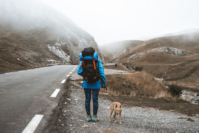 Rear view of man with dog walking in snow