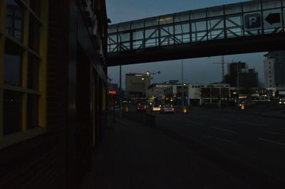 Road by illuminated city against sky at night