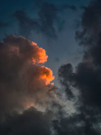Orange sliver of color on clouds at sunset dusk in between dark stormy skies.