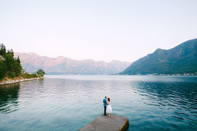 People on lake against clear sky