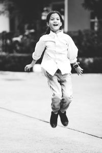 Full length portrait of smiling girl standing on footpath