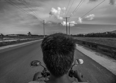Rear view of woman on street against sky