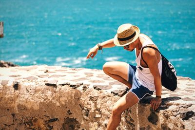 Full length of young man on retaining wall against sea