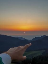 Midsection of woman against mountains during sunset