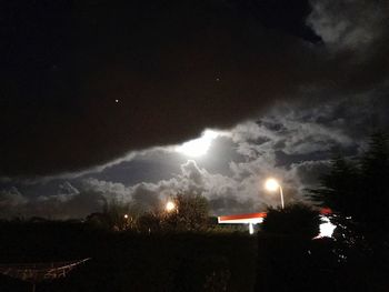 Storm clouds over illuminated mountain at night