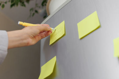 A woman makes notes on colored stickers on the refrigerator. a reminder or a note for her husband