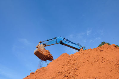 Low angle view of crane at construction site against sky