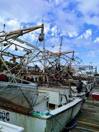 Fishing boat moored at harbor against sky