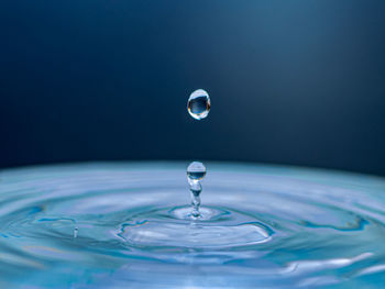 Close-up of drop falling on water against black background