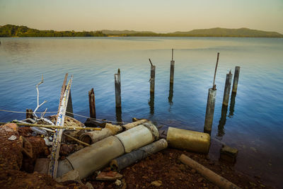 Wooden posts in lake against sky