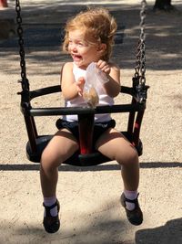 Cheerful girl sitting on swing at park