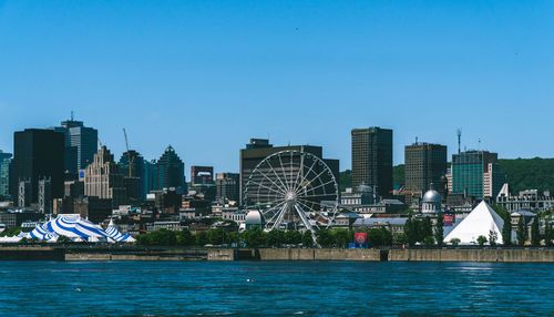 River by modern buildings against clear blue sky