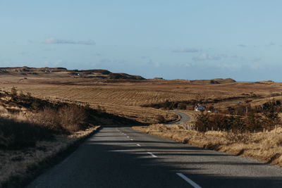 Road amidst field against sky