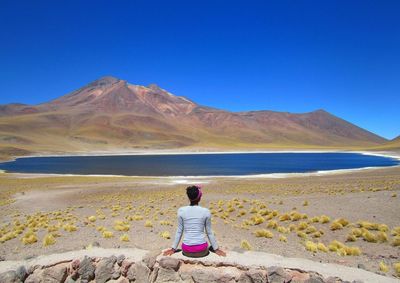 Rear view of woman looking at mountains against clear sky