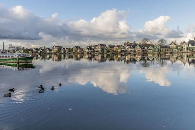 View of birds swimming in lake against cloudy sky