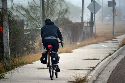 Rear view of man cycling on sidewalk 