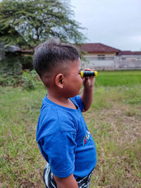 Little boy playing binoculars on the edge of the rice field