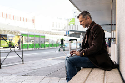 Side view of young man using mobile phone