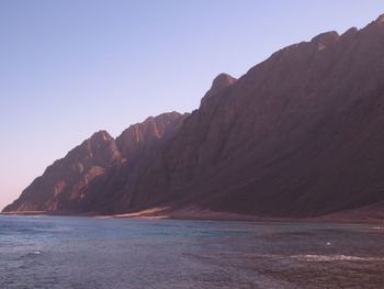 Scenic view of sea and mountains against clear sky