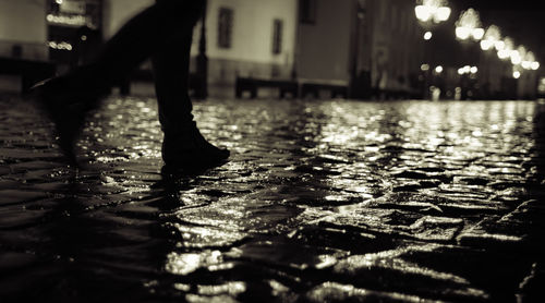 Low section of man standing on wet street