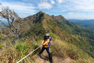 Man cycling on mountain against sky