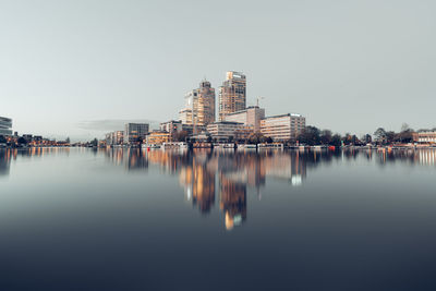 Scenic view of lake by buildings against clear sky