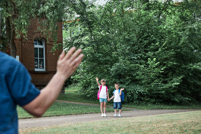 Dad takes the kids to school or kindergarten, stands and waves at them. happy kids return to school 