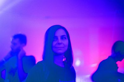 Young woman standing against illuminated wall at night