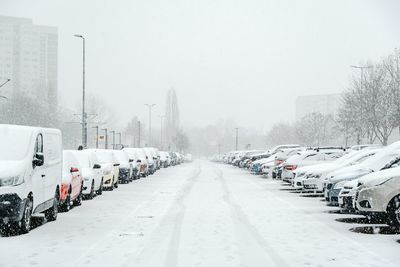 Snow covered road against sky in city