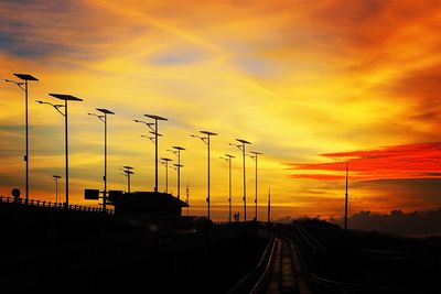 Silhouette railroad tracks against sky during sunset