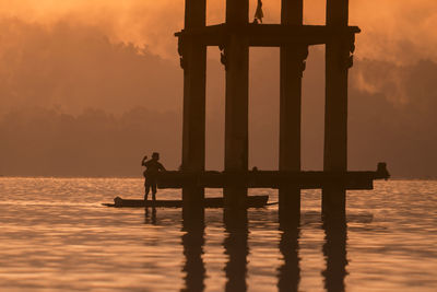 Man standing by in river during sunset