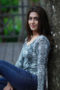 Portrait of young woman sitting against wall