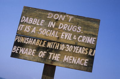 Low angle view of wooden sign board against sky