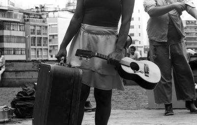 Street musician holding guitar and bag