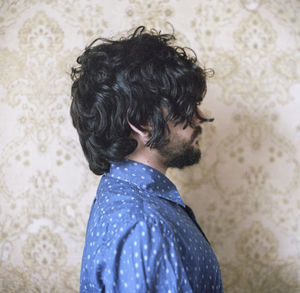 Rear view of man standing against wall at home