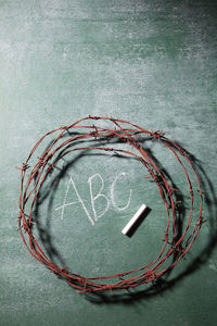 Close-up of rusty barbed wire with chalk on blackboard