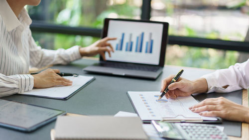 Coworker business concept, two businesswoman pointing on chart financial to discussing together.