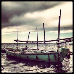 Boats in sea against cloudy sky