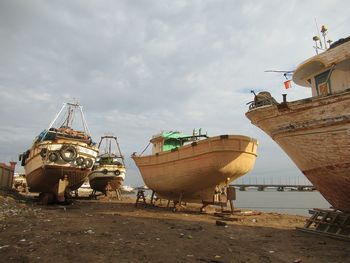 Fishing boats moored on beach against sky