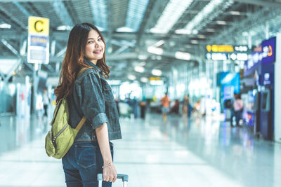 Full length of smiling woman standing at airport
