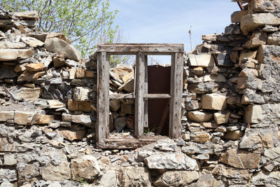 Wooden window on damaged stone wall