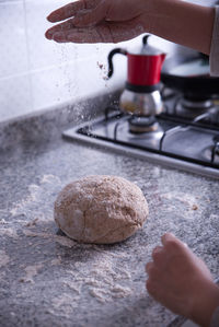 Woman's hands preparing homemade bread dough in a kitchen.