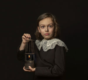 Portrait of young woman holding wineglass against black background