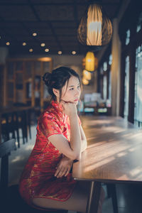 Young woman looking away while sitting at table