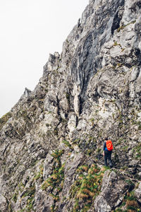 Rear view of hiker with backpack walking on cliff during foggy weather