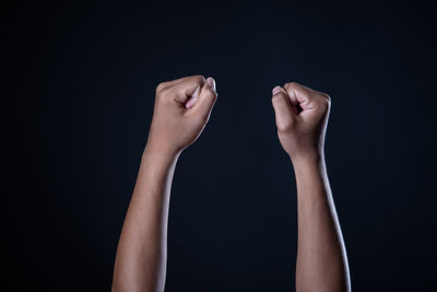 Midsection of woman holding hands against black background